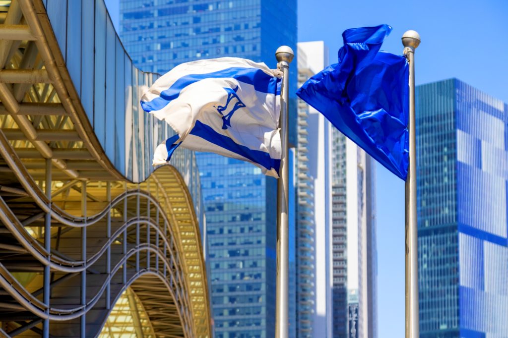 Bandeira de Israel com prédios da cidade de Tel Aviv ao fundo