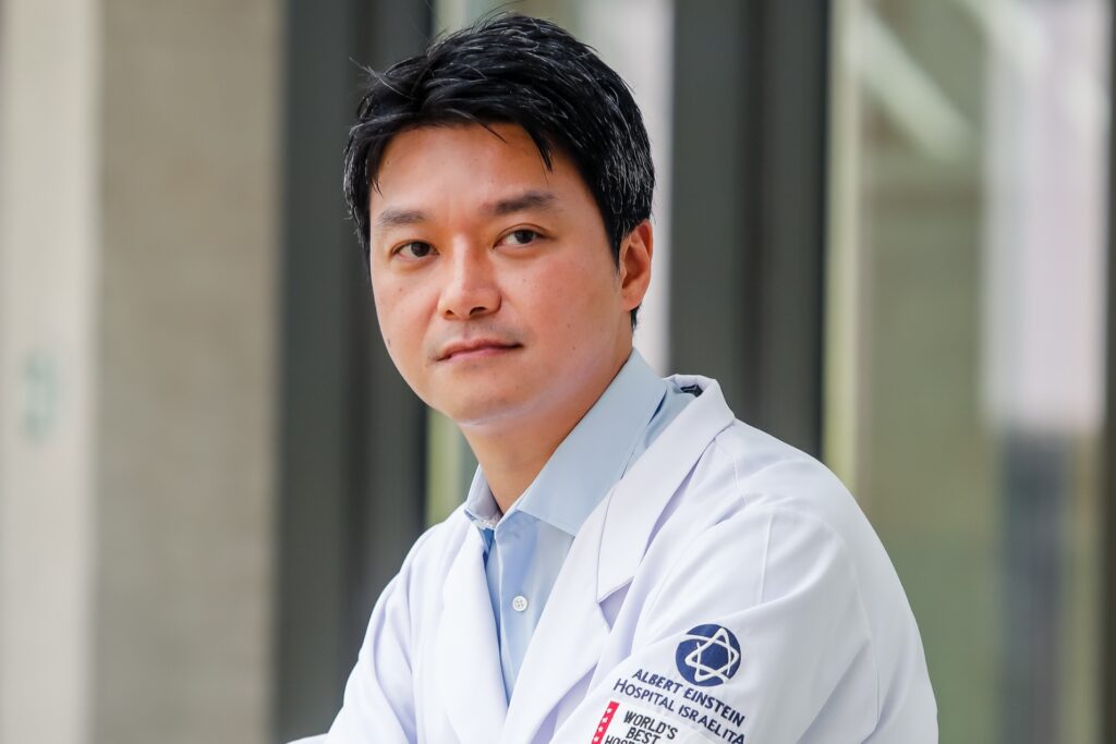 Dr. Nam Jin Kim, do Einstein, olhando para a direita, com camisa azul e avental branco
